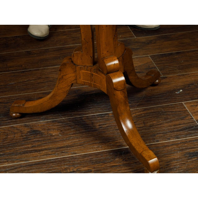 An Austrian Biedermeier period walnut guéridon table from the 19th century with radiating veneer and banding. Created in...
