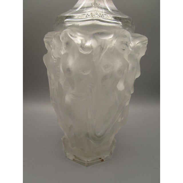 This frosted glass decanter features intricate relief designs of dancing nude woman, showcasing artistic craftsmanship....