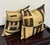 Design Plus Gallery presents a Pair of Kuba Cloth Decorative Pillows. Black, tan, and caramel woven textile panels form...