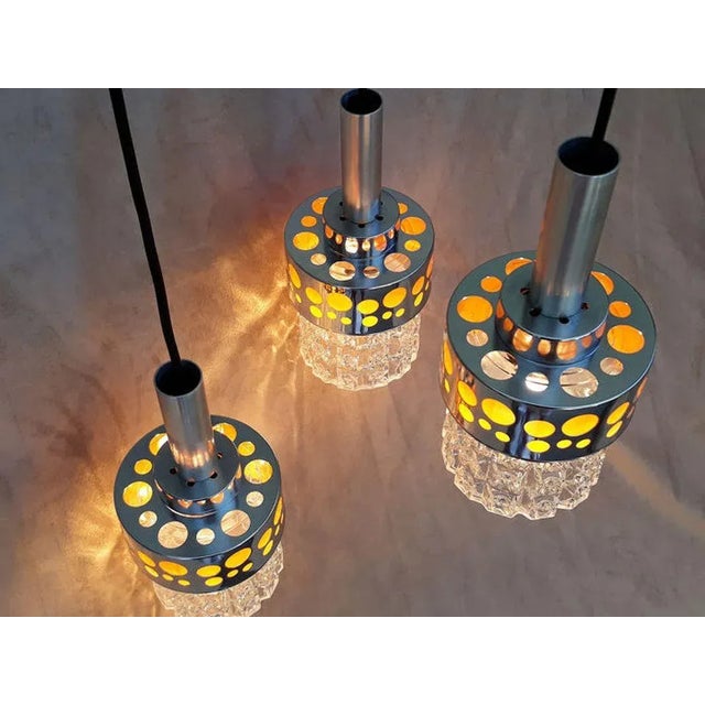 Vintage space age style chandelier. The three chrome metal elements, inlaid with orange, diffuse a warm light with a...