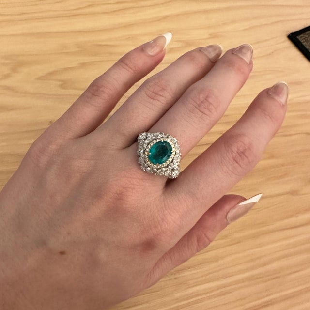 This emerald A Colombian emerald shines in a pure, vivid green at the heart of this solid 14K yellow gold ring, flanked by...