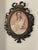 Vintage lady’s neoclassical portrait lithograph in metal ornate frame. 4” by 3”. Oval conclave glass cover.