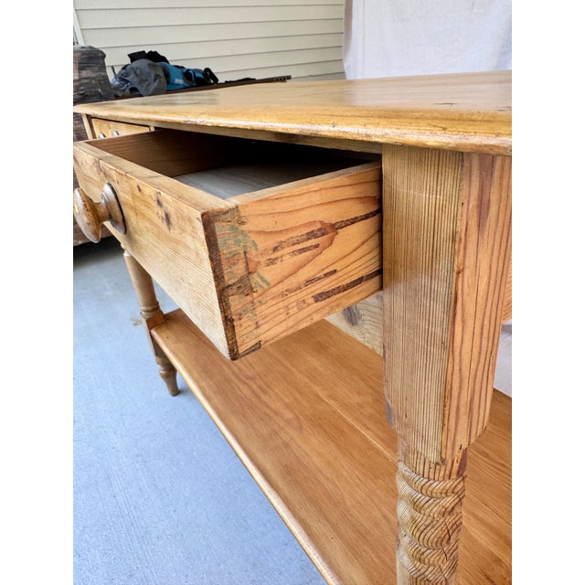 This attractive and timeless English pine console table has a rectangular shape, raised on four turned legs, and has a...