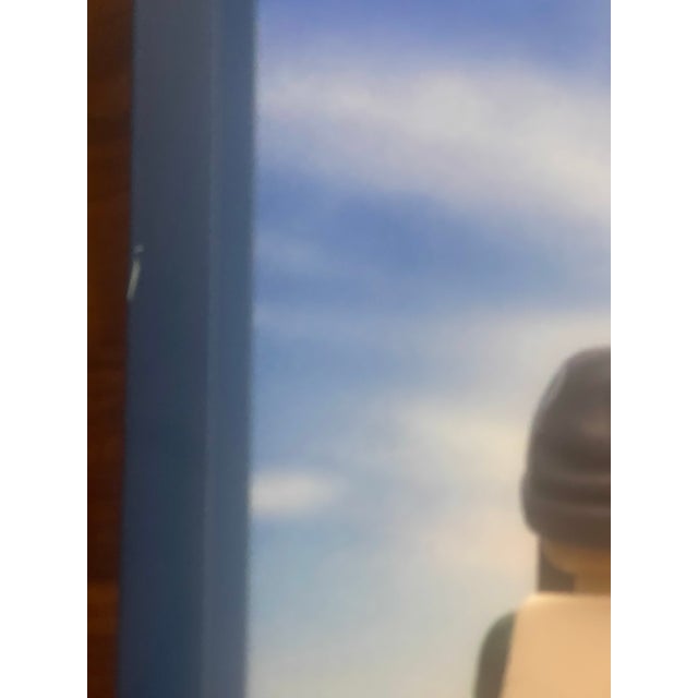 A playful and thoughtfully composed framed photographic print featuring a LEGO figure posed as a traveler overlooking the...