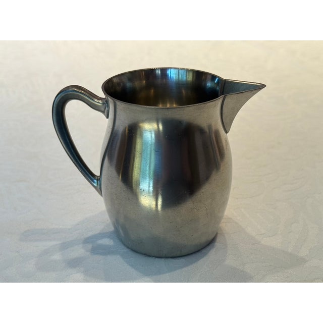 This exceptional Mid-Century Modern sculptural pitcher exemplifies the restrained elegance of post-war European metalwork....