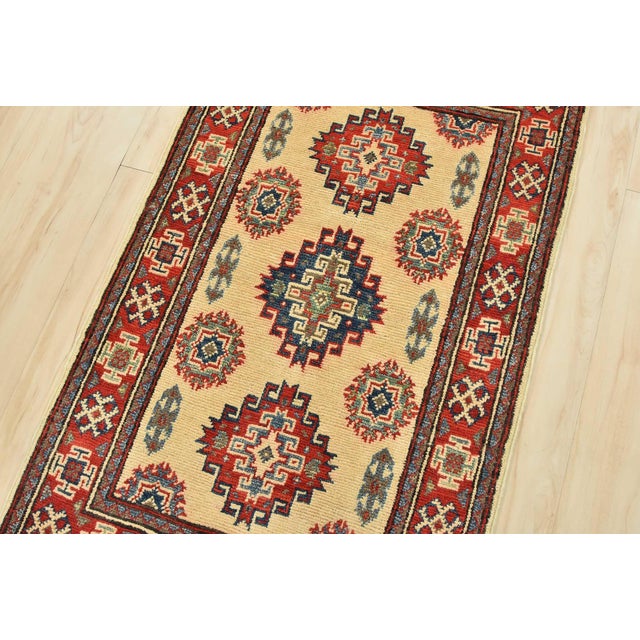 A tribal Caucasian Kazak rug is hand-knotted with an all-wool pile on a cotton foundation. This oriental rug features...