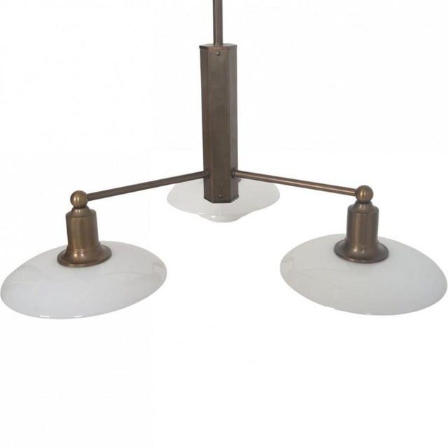 Poul Henningsen 100 Year anniversary chandelier with a frame of browned brass and white opal glass shades. The lamp is...