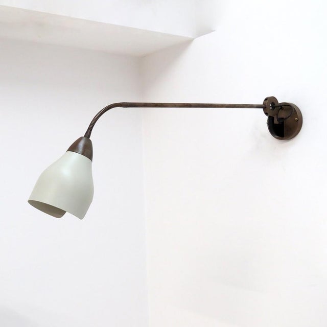 Large-scale Italian swing arm wall light in patinated brass, with a crème colored shade on a goose neck extension. the...