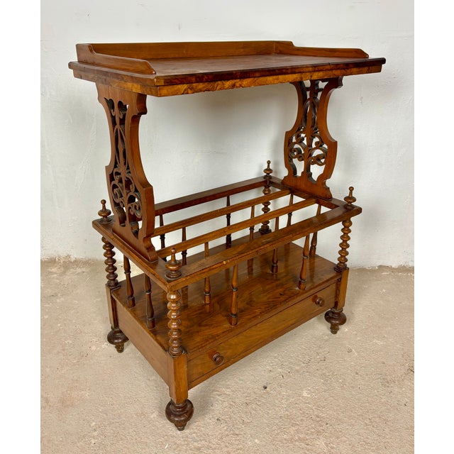Elegant Victorian walnut Canterbury featuring a removable tray top, open slatted storage compartment, and a lower drawer....