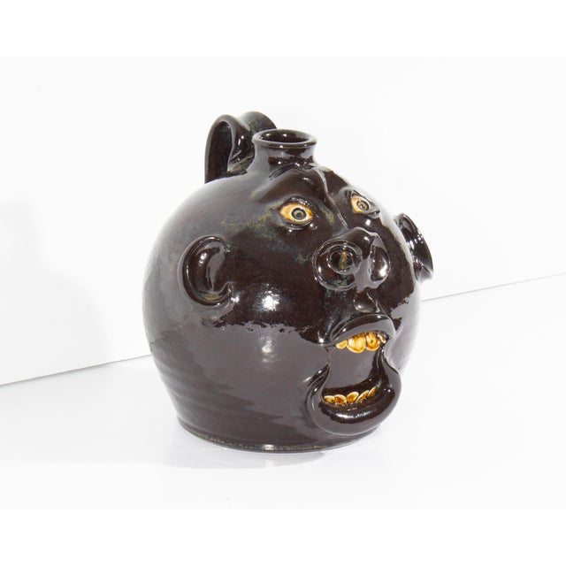 A 2000 Georgia folk art face jug by the American ceramicist Roger Corn. This ceramic piece features a stylized face, its...