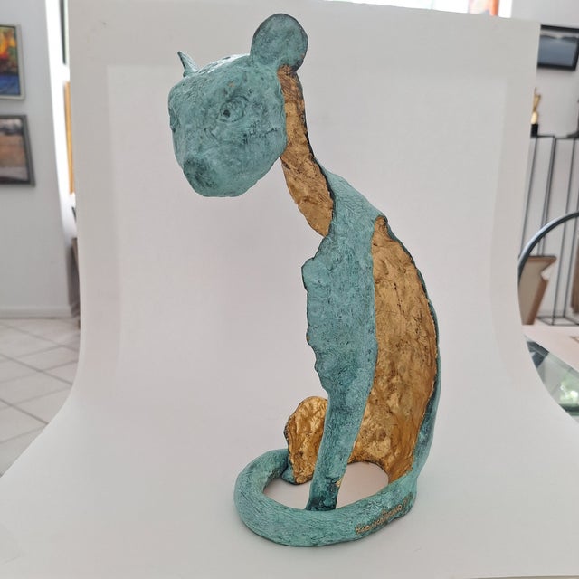This striking sculpture artistically captures the essence of a sitting cat using elegant abstraction. Crafted with a rich...