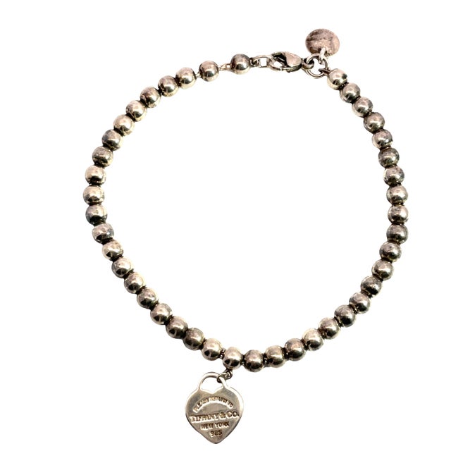 A charming vintage Tiffany & Co. bead bracelet crafted in sterling silver, featuring signature charm: a classic “Please...