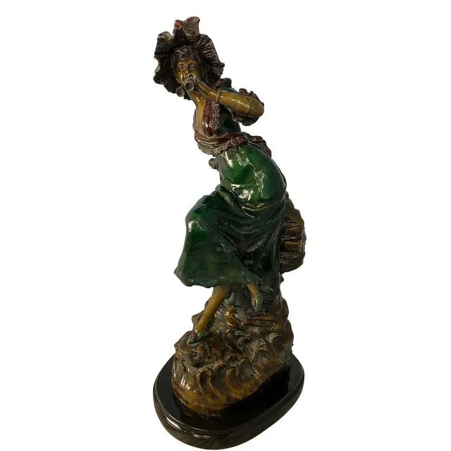 A fine 20th century statue of a two-tone patina bronze woman dressed in classic victorian clothing, holding a pair of...