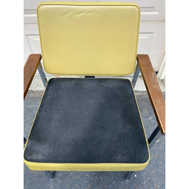 Mid-century modern yellow vinyl and black fabric office chair. Chrome base with wood arms. Some minor tears on the back of...