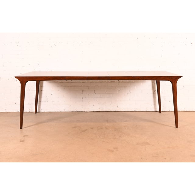 A sleek and stylish Mid-Century Modern sculpted walnut extension dining table By John Van Koert for Drexel, "Profile"...