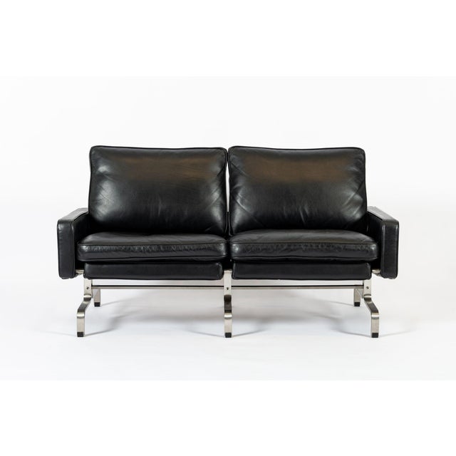This incredible vintage postmodern black leather loveseat couch in the style of Poul Kjaerholm is circa 1980. The unique...