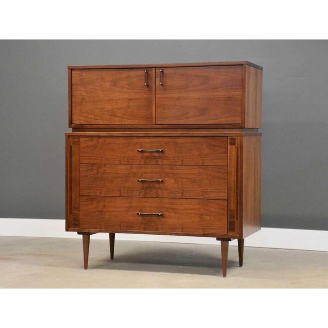 A mid century modern walnut tall dovetail drawer dresser with two doors and rosewood drawer pulls made by Kroehler...