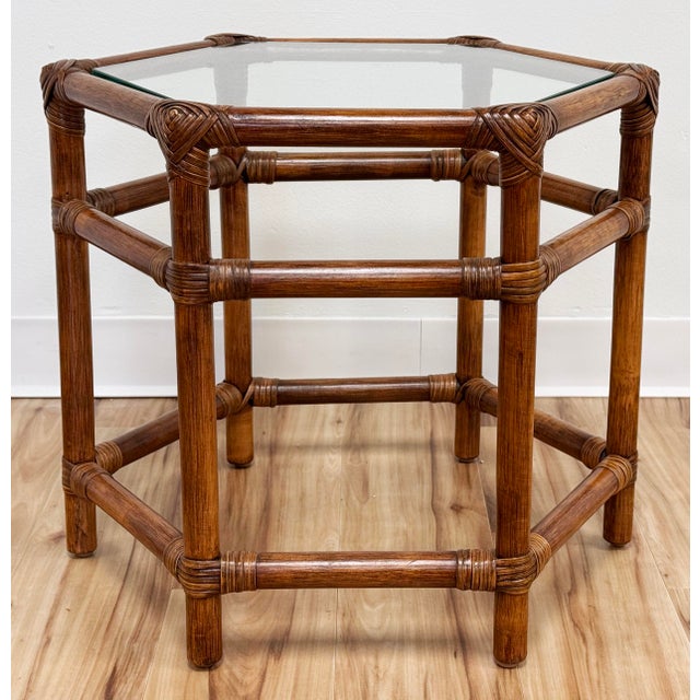 Vintage hexagonal shaped rattan side table with inset glass top. Measures 18.5"H. Natural age wear. No chips or cracks to...
