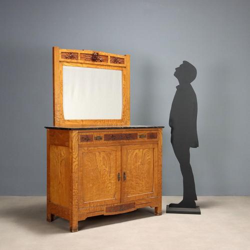 Art Nouveau oak chest of drawers. Front with paneled doors and a drawer beneath the top carved with floral and leaf...