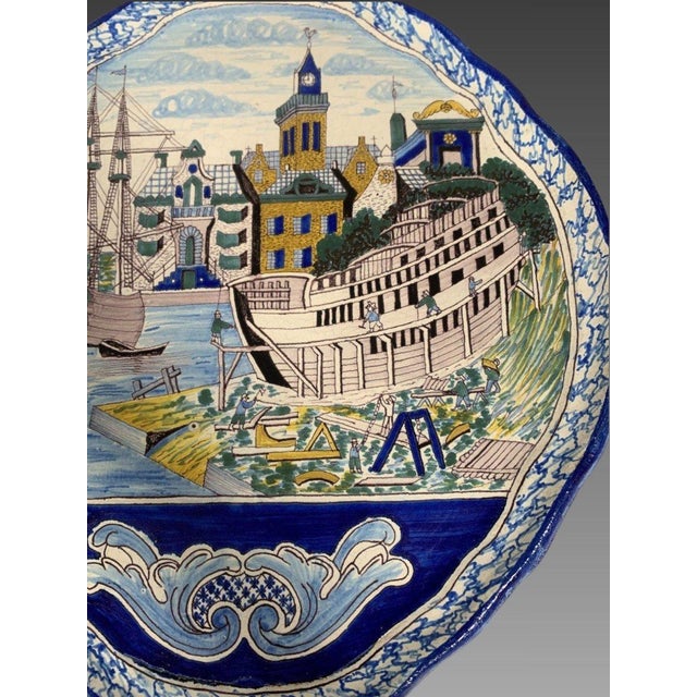 MAKKUM (NEW FRISE) Large polychrome decorated earthenware wall plaque depicting a shipyard scene in a Dutch town. The blue...