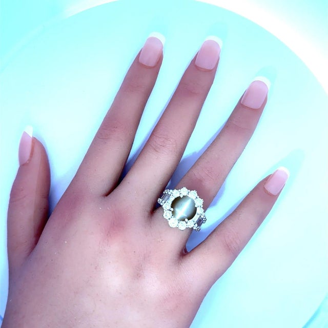 A striking and elegant ring featuring a natural cat’s eye chrysoberyl as the centerpiece, weighing 5.26 carats. The golden...