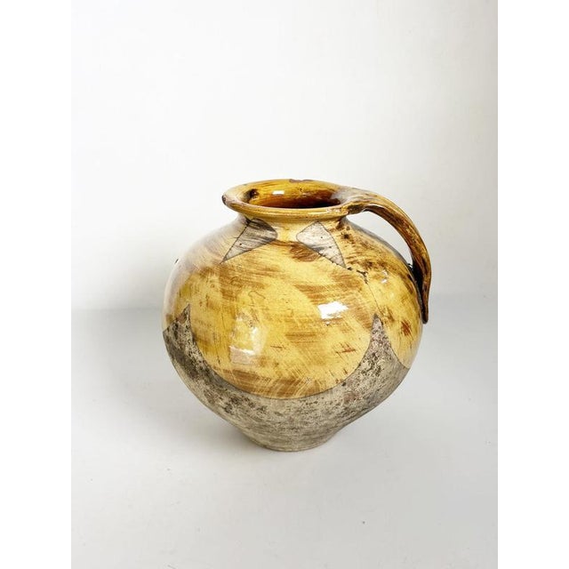 French glazed pottery jar dating from the 1960s, featuring a generous rounded body and a large integrated handle. The...