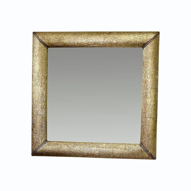 Moroccan brass metal mirror, characterized by its luxurious golden sheen and intricate embossed arabesque patterns that...
