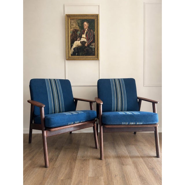 A handsome pair of Danish modern teak lounge chairs in the style of Hans Wegner, made in Denmark, circa 1960s. The chairs...