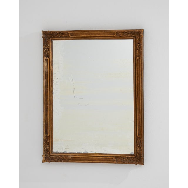 A decorative wall mirror featuring a carved giltwood frame, embodying classic French elegance. The intricate detailing...