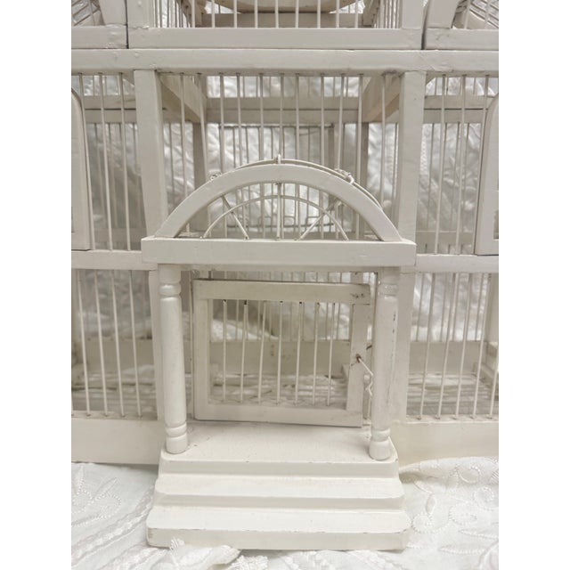A striking decorative birdcage designed as a miniature architectural pavilion, finished in a soft painted white. Its...