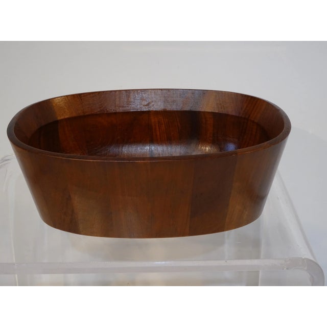 A darker toned teak wood oval shaped bowl designed by Jens H. Quistgaard who is known for his earthy sculptural pepper...