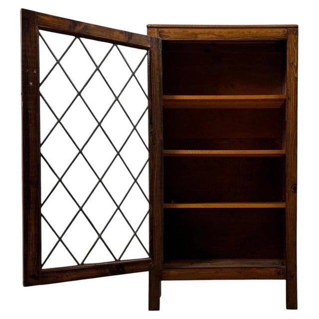 A charming 20th-century English display cabinet, crafted from pine and distinguished by its leaded glass door, compact...
