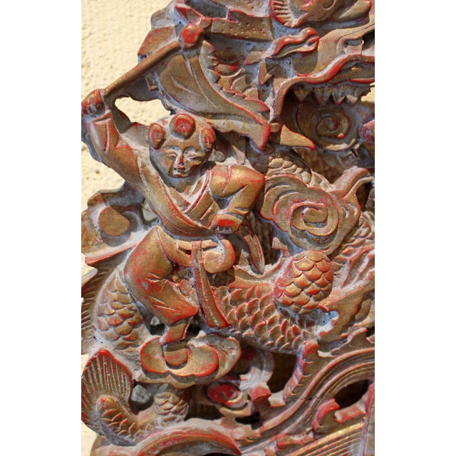 Mid-20th century carved Chinese panel. Centered by a temple being attacked by dragons from both sides with guards...