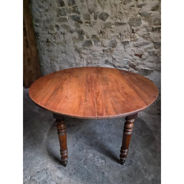 Antique French drop-leaf dining table dating from the late 19th century, circa 1870–1900. The table has a cherrywood top...