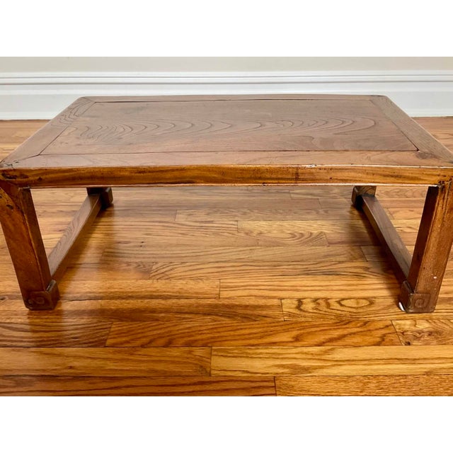 An antique Chinese low table exuding Ming Dynasty simplicity with a natural wood grain finish and simple rectilinear legs...