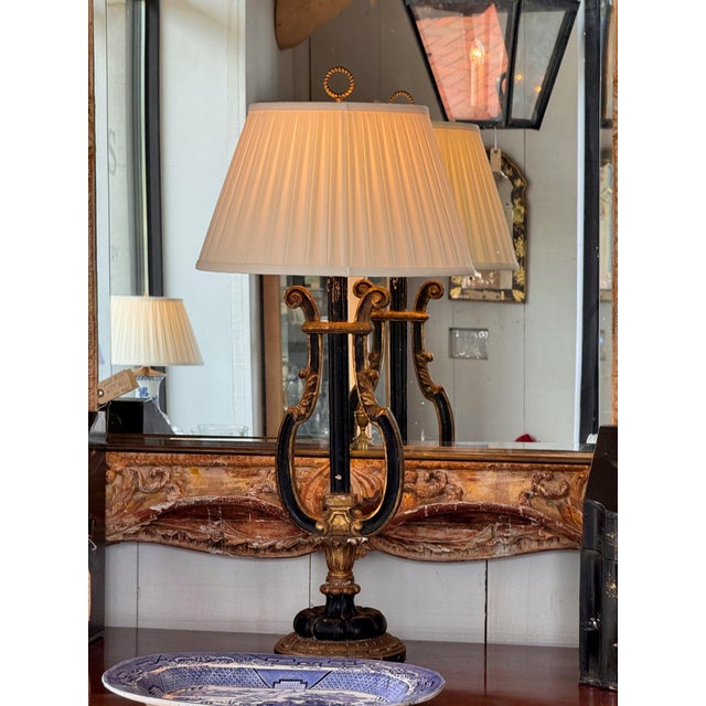 Vintage Italian lamp carved as a lyre in ebonized wood picked out with gilt. Two arms curve up from a gilt cartouche to...