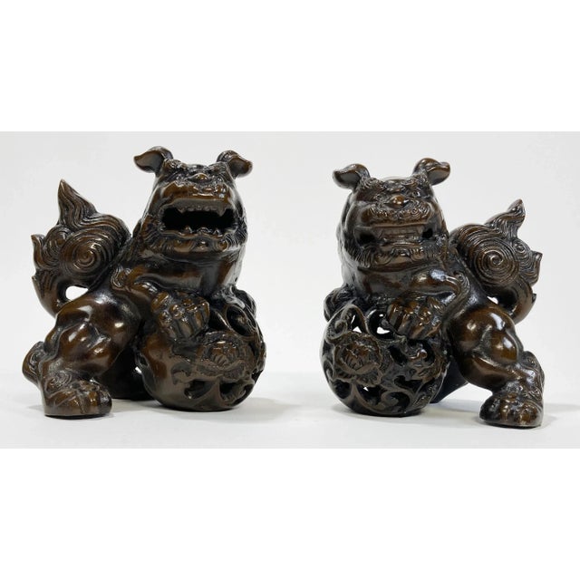 A substantial, heavy stone pair of partnered Foo Dog statues with a deep bronzed finish. Wonderful on a mantle or as...