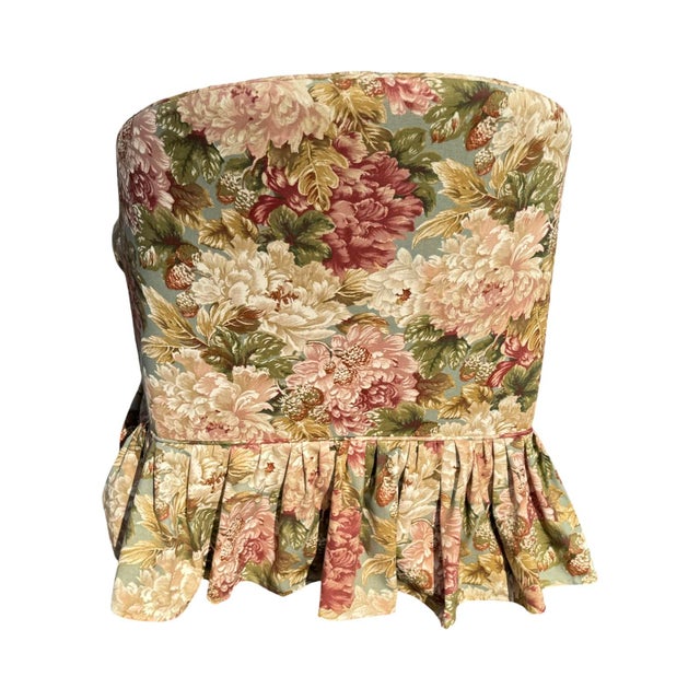 Floral upholstered arm chair with ruffled skirt concealing the legs, rolled arms and gathered pleated trim that...