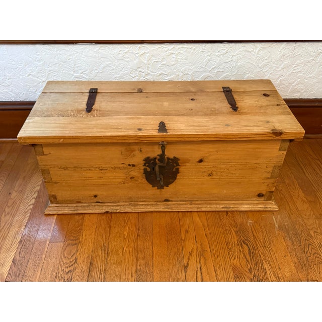 A vintage knotty pine trunk with iron strap hinges and hardware. Lovely at the foot of a bed or as a coffee table....
