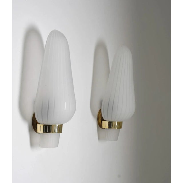 Pair of wall lights or sconces manufactured in Sweden in the 1940s. Each lamp features one light source, hidden by a large...