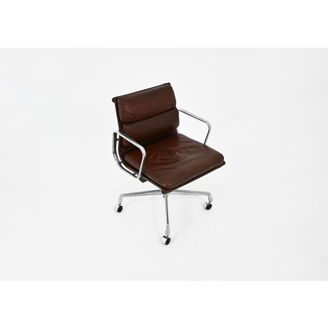 Brown leather armchair with an aluminum base and wheels. The chair swivels. Stamped Herman Miller. Wear consistent with...