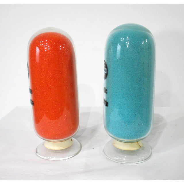 A pair of handblown inverted glass pharmaceutical advertising display bottles one in blue with Copric Chloride and in...