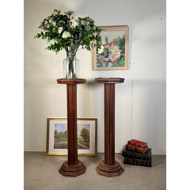 This pair of antique French tall carved oak plant stands, sourced in France, showcases elegant craftsmanship and timeless...