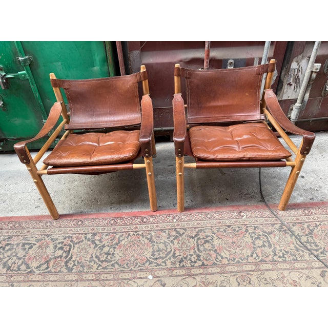 A pair of “Sirocco” safari chairs by Arne Norell, produced by Arne Norell AB in Sweden, 1960s. Crafted in solid oak with...