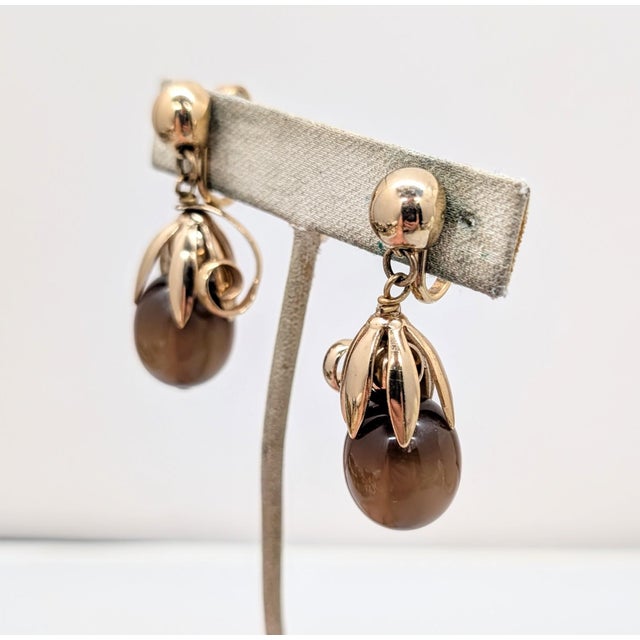 1950s goldtone round domed top with brown moonglow resin drop with curled top "cumquat" clip earrings. Marked "NAPIER" in...