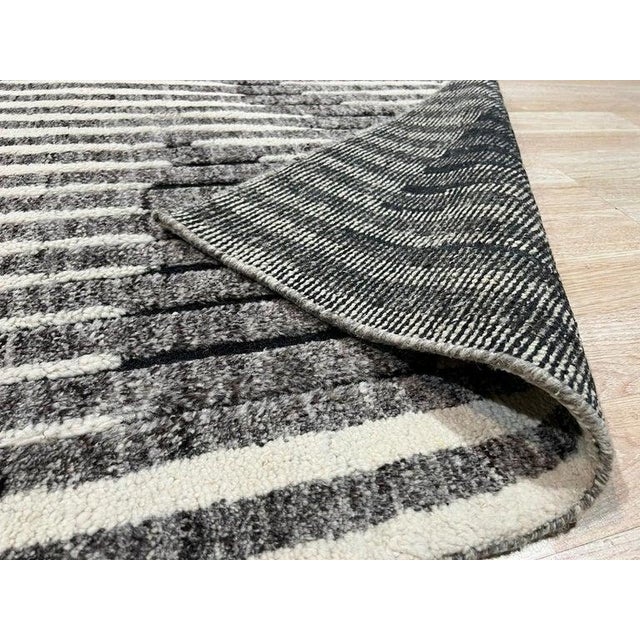 This gray wool rug features a hand knotted pile construction and originates from India. The design is defined by an...