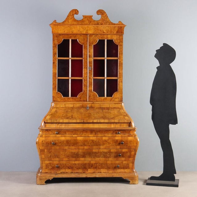 Walnut and burl walnut trumeau. Glass-door cabinet with a central drop-down door concealing a four-drawer cabinet, the...