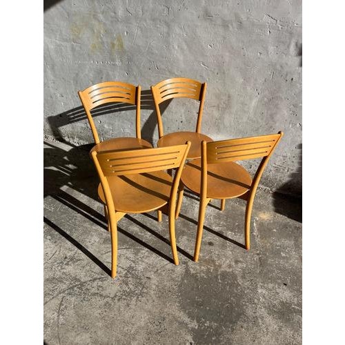 Set of four vintage Italian bistro dining chairs from the 1980s. Crafted in solid wood with a warm honey-toned finish,...