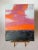 Striking and radiant sunset clouds and colors over a dim dusky landscape. The simplicity of this piece with the texture of...
