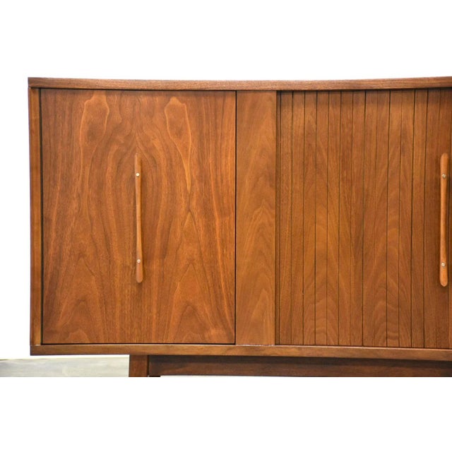 A mid century modern walnut credenza with tambour doors and sculpted pulls and brass accents. 71.75” wide. 18” deep. 33”...